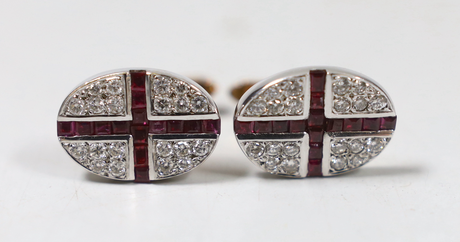 A modern pair of 9ct gold, ruby and diamond cluster set oval cufflinks, with cross motif, 21mm, gross weight 17.9 grams.